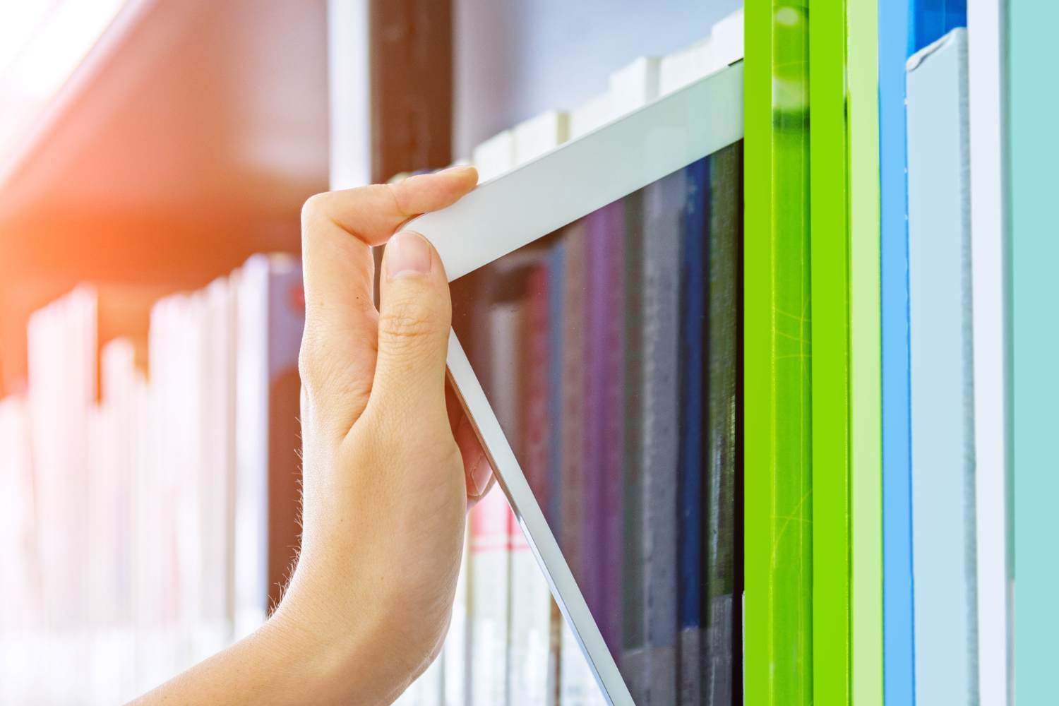 A person taking an ipad from a bookshelf